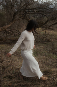 Model walking showing side of oat true knit cotton sweater.