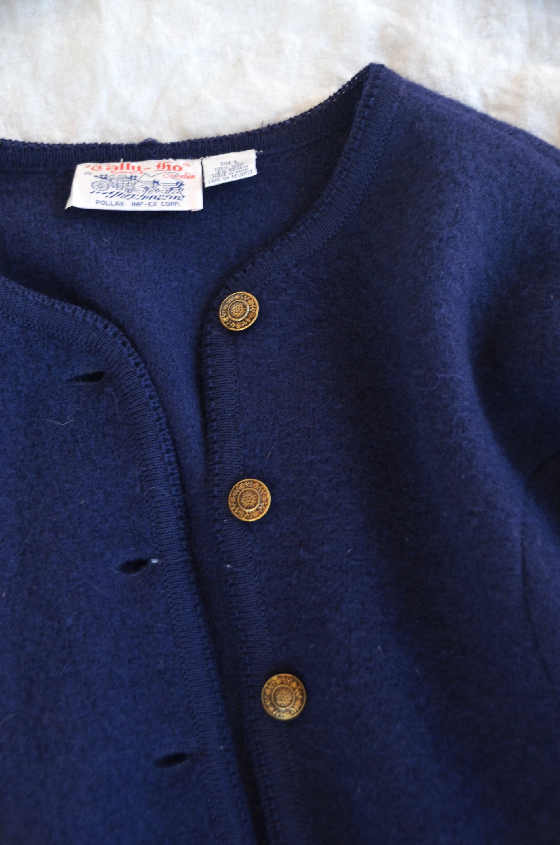 close up image of midnight blue wool coat or cardigan with floral button detail